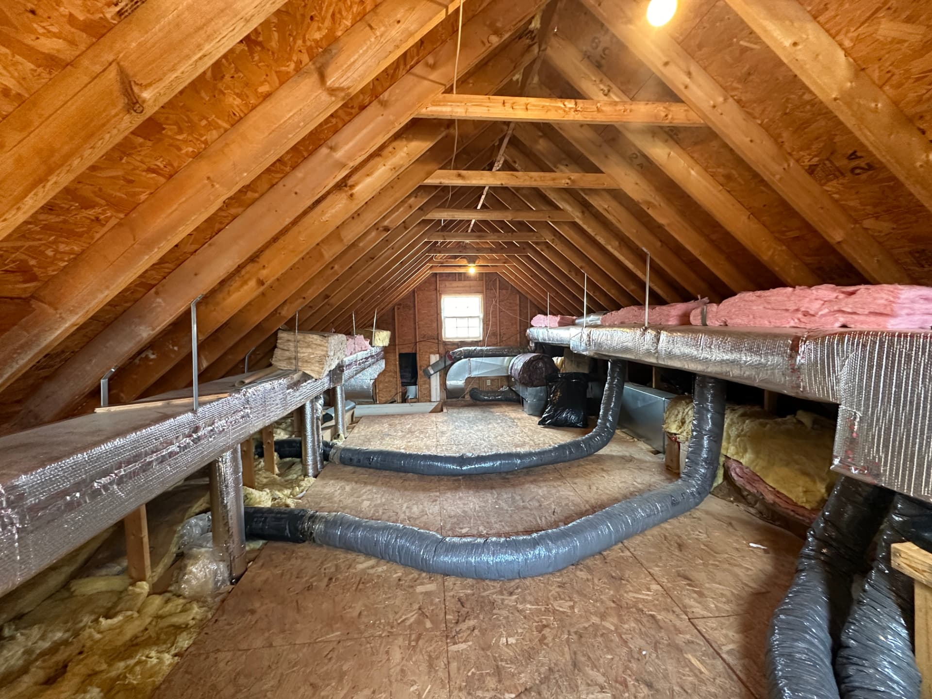 Attic space with wood framing, plank flooring, and heating ductwork