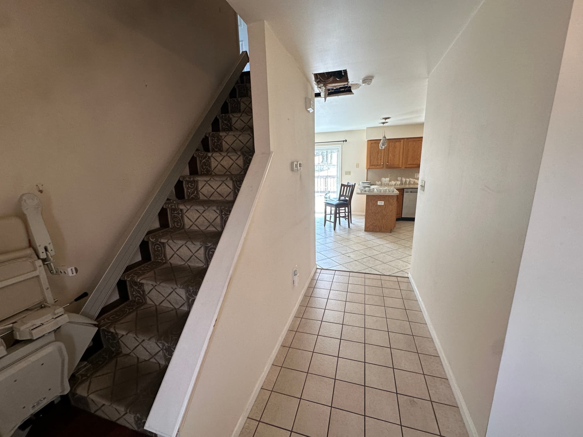Entry hallway with tile flooring and a carpeted staircase leading upstairs